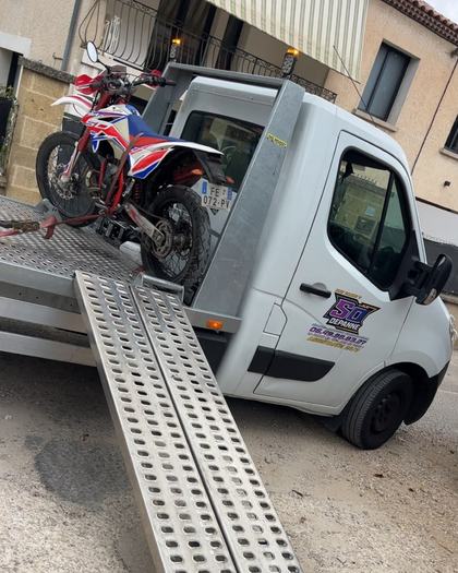 Moto cross sanglée sur le plateau du camion de dépannage SO DEPANNE, rampes de chargement déployées