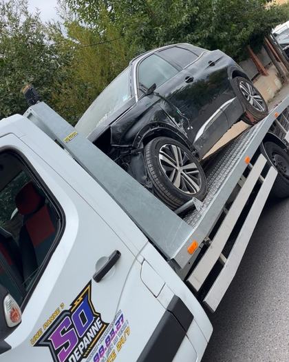 SUV noir accidenté, avant endommagé, chargé sur le plateau de remorquage SO DEPANNE
